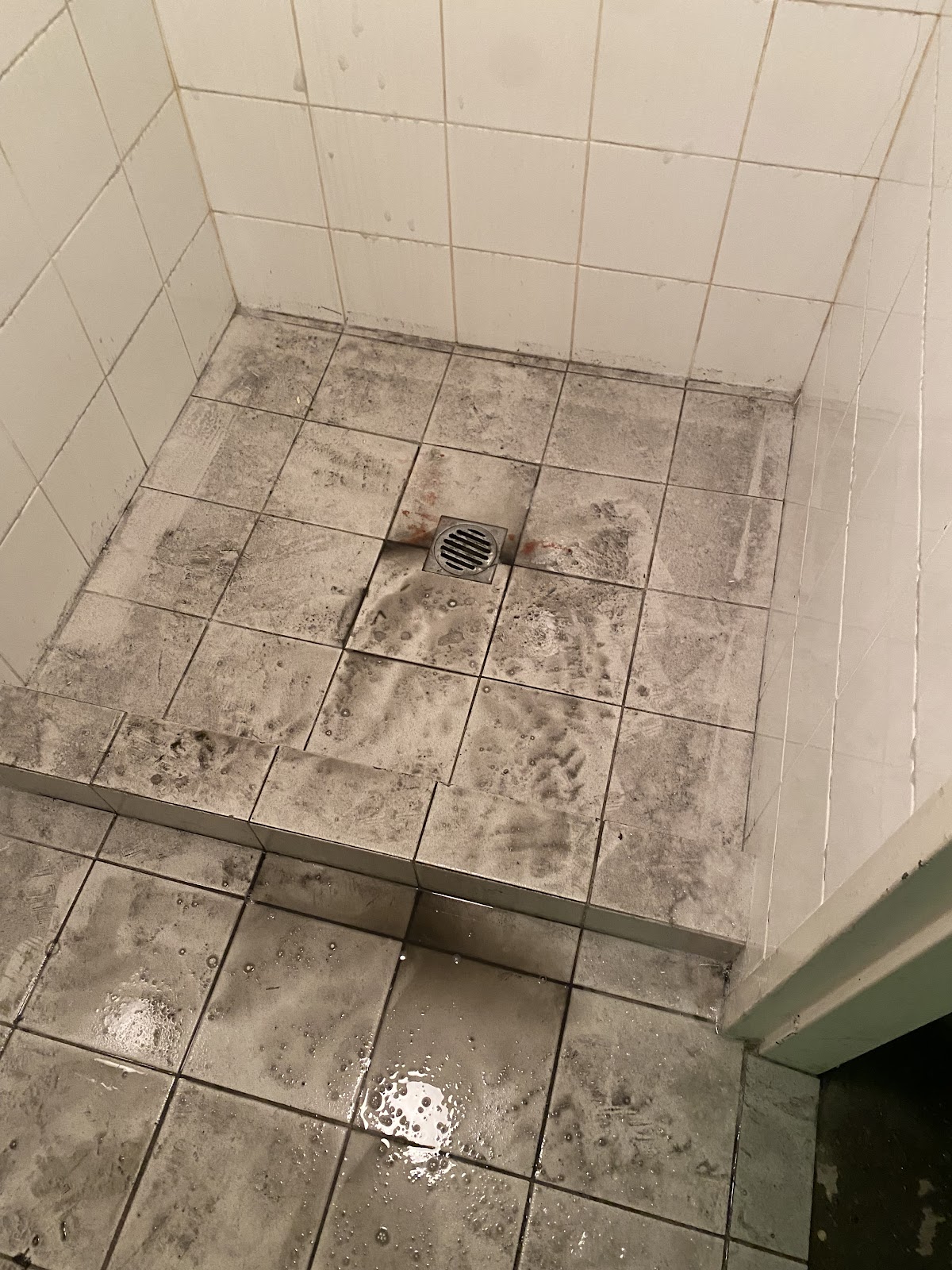 Before: a shower floor covered in grey soap scum and grime
