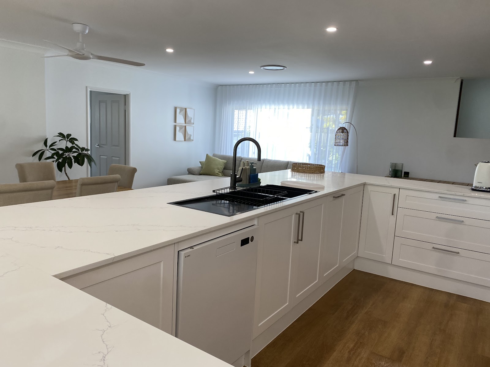Open plan white kitchen, benchtops clear and floors clean