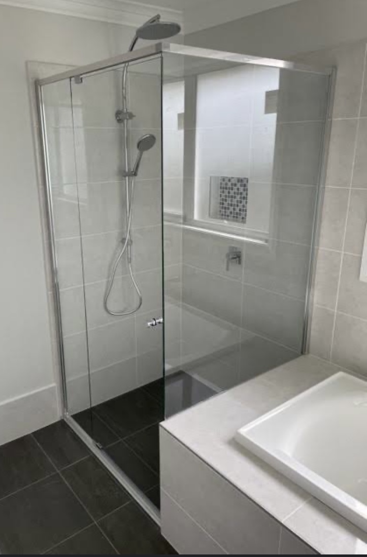 Framed glass shower above a tiled bath, glass and tiles gleaming